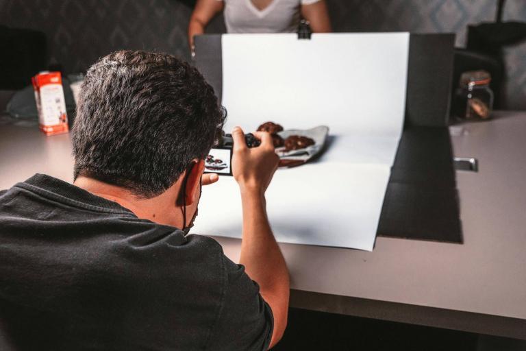 Back view of a photographer taking food photos on a tabletop setup.